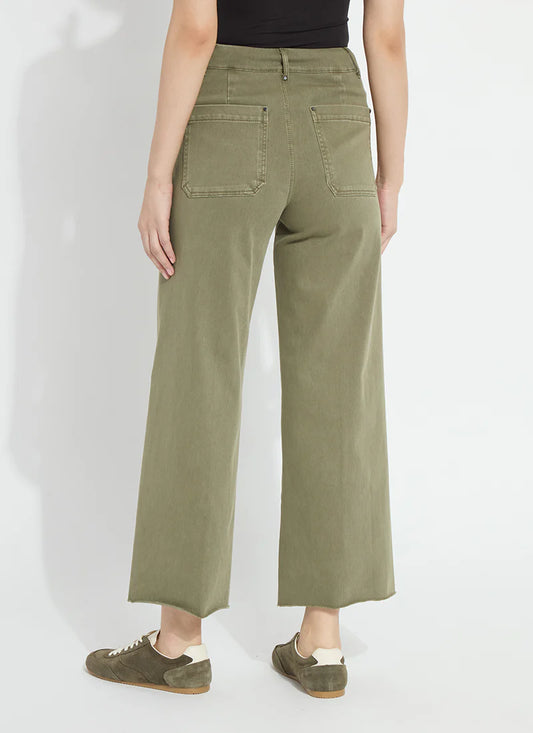 A model shown from the back wearing olive green wide-leg cropped pants, a black top, and olive green suede sneakers against a white studio background.
