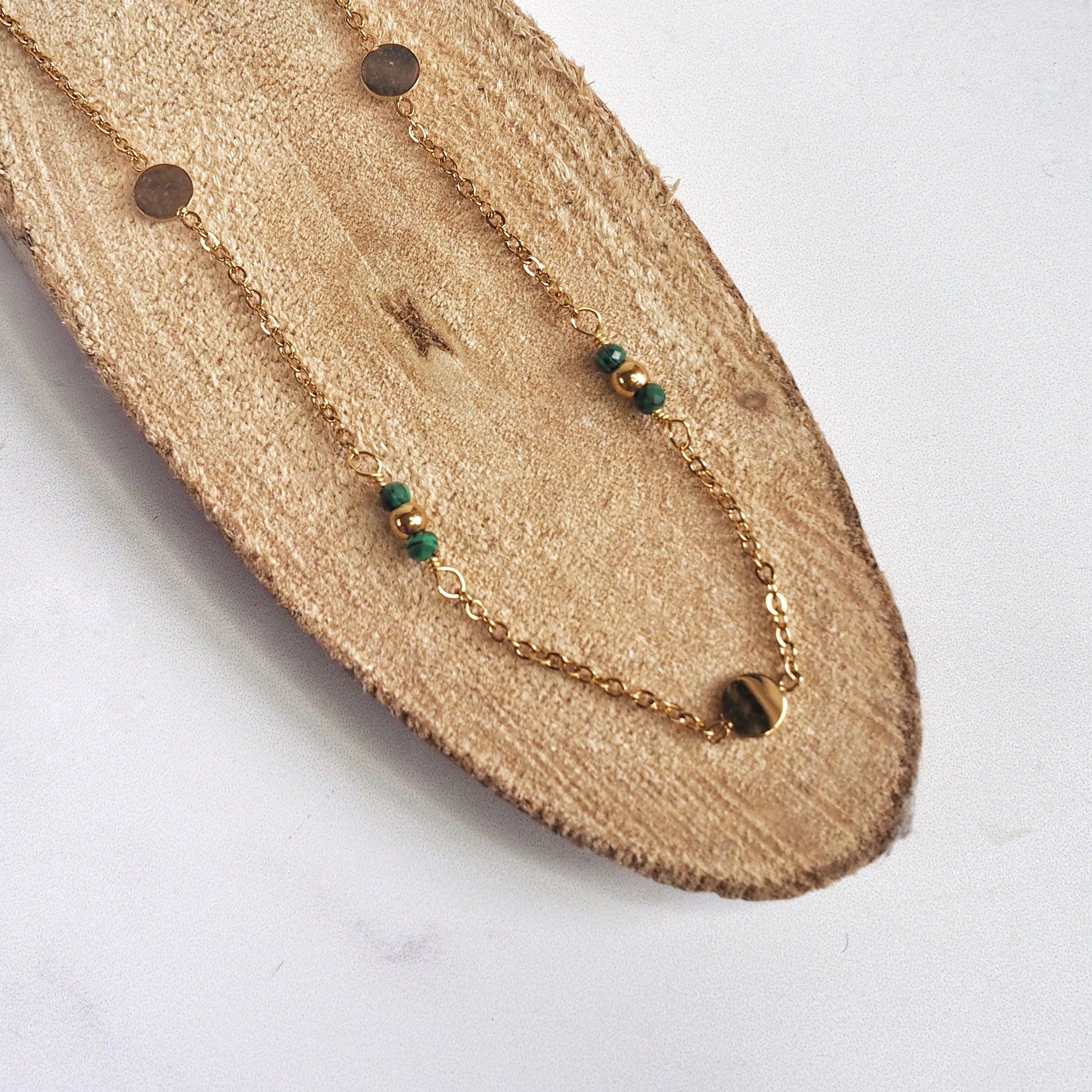Gold necklace with green beads on a wooden surface