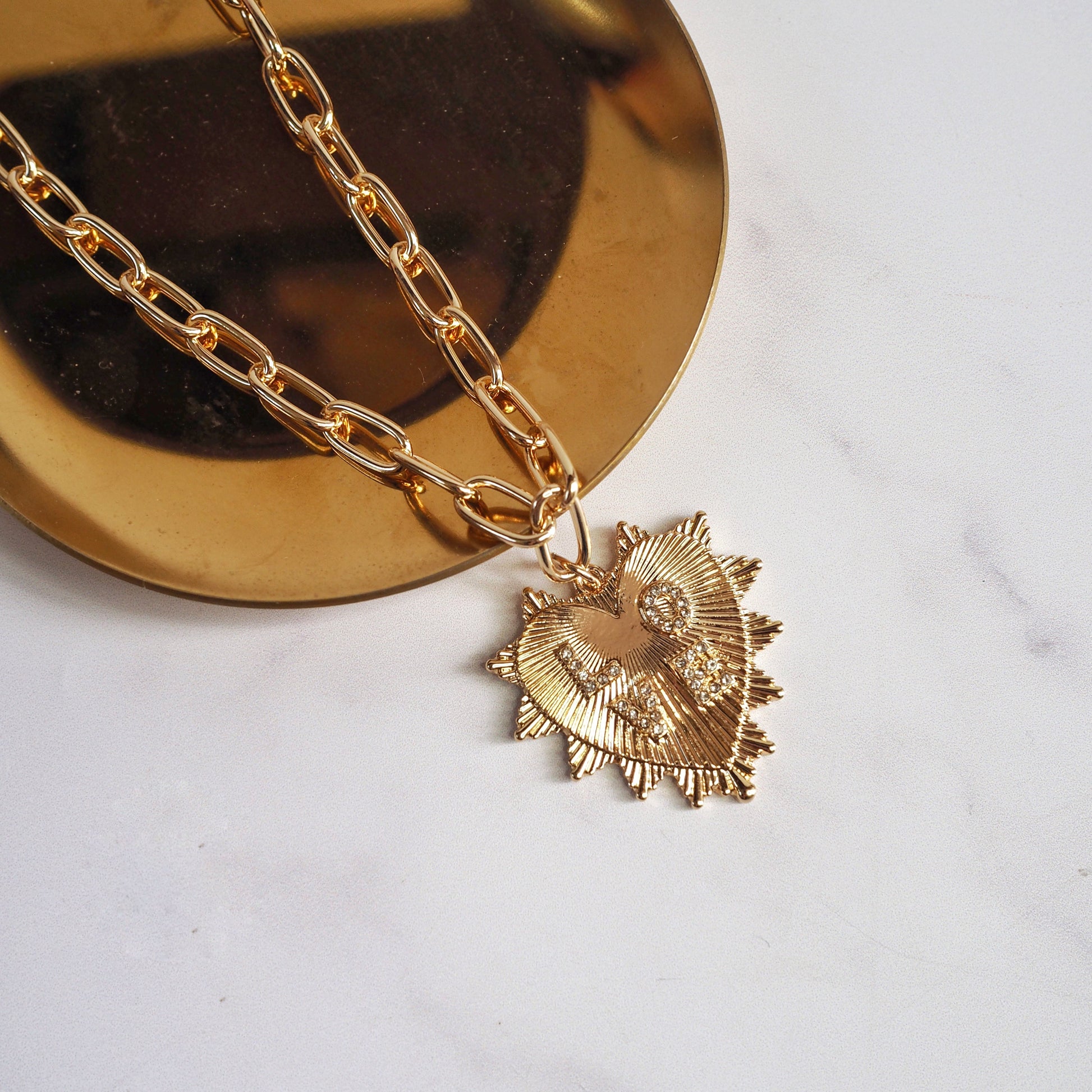 Gold necklace with a heart-shaped pendant on a white background