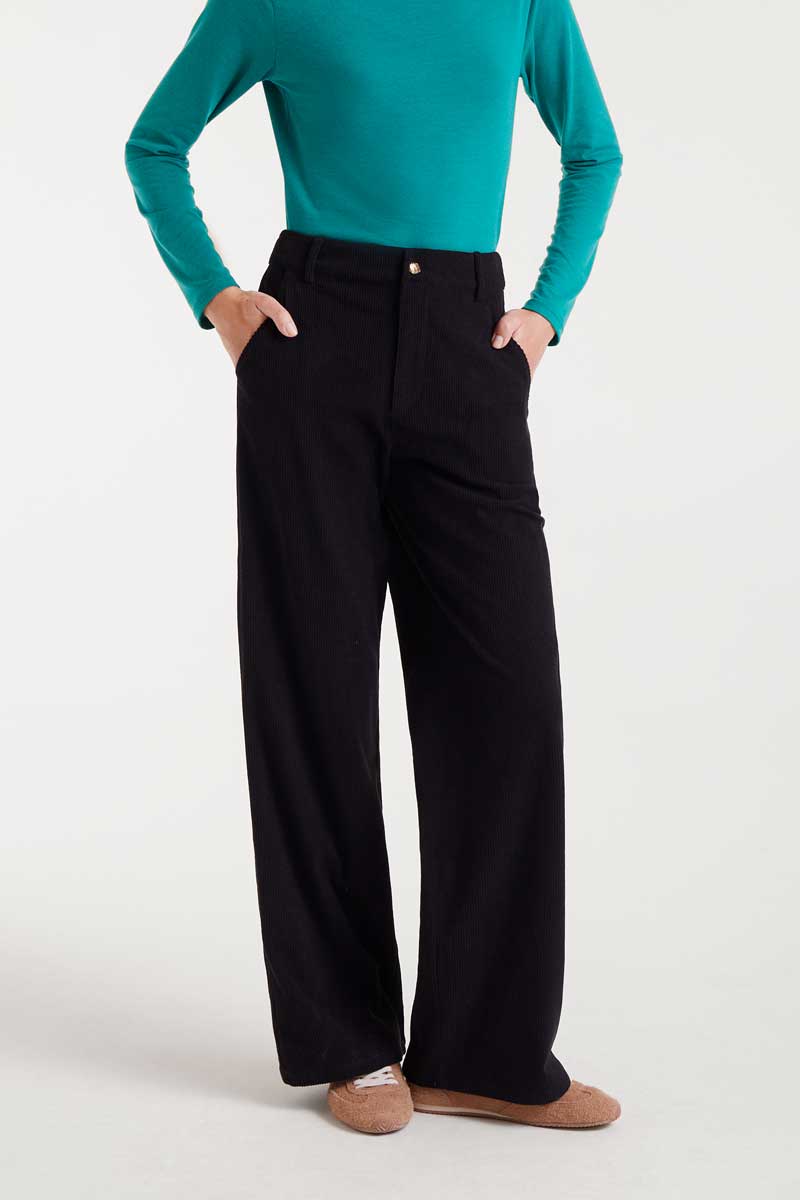 Person wearing a teal top and black pants on a white background