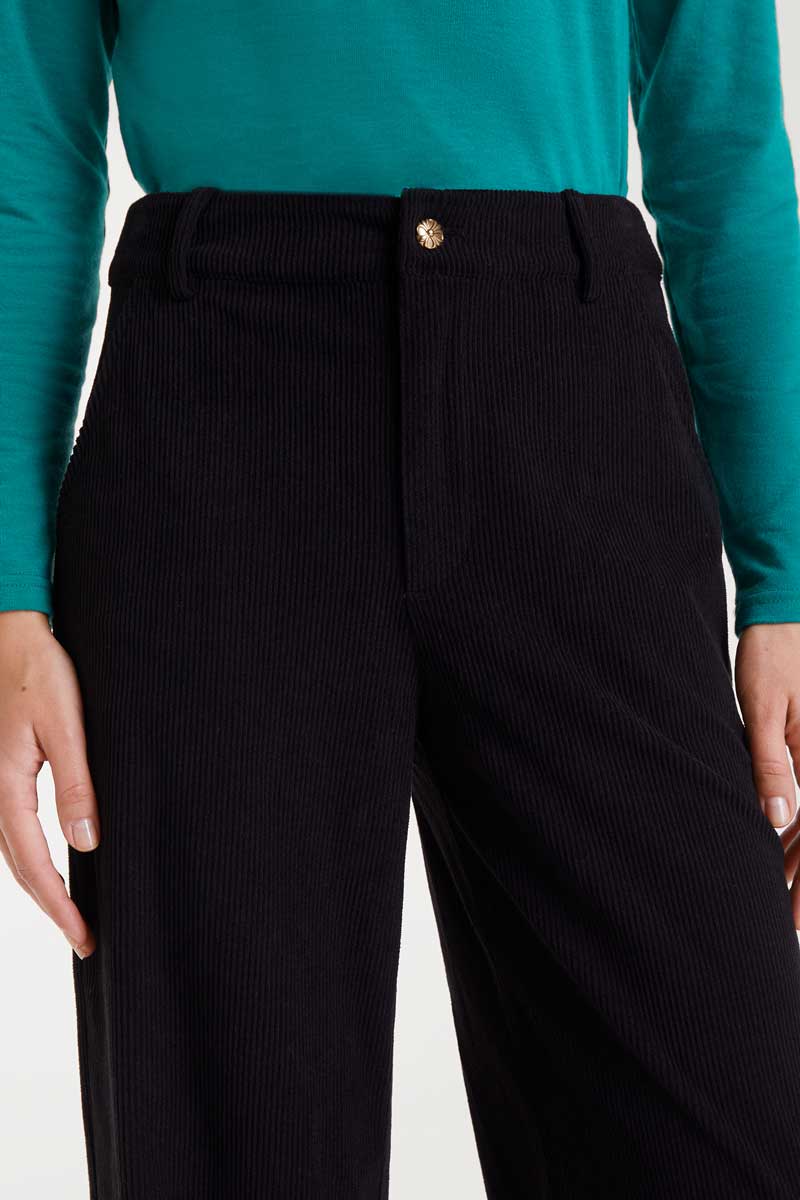 Person wearing a teal long-sleeve top and black high-waisted pants on a white background