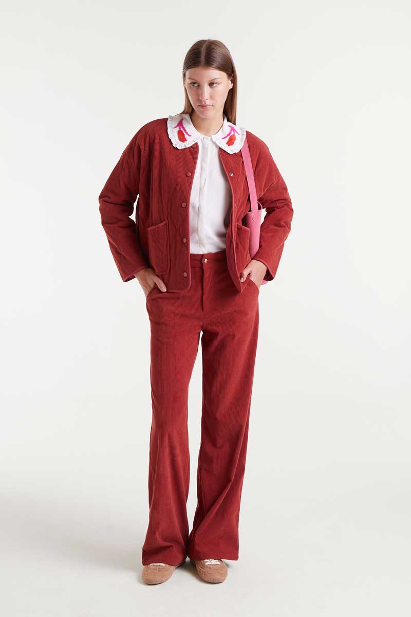 Woman wearing a red outfit with a white shirt and collar on a white background