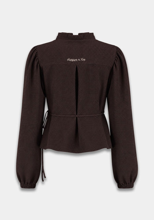 A dark brown textured long-sleeve blouse with a mock neck, puff sleeves, and a drawstring waist, shown from the back on a light gray background.