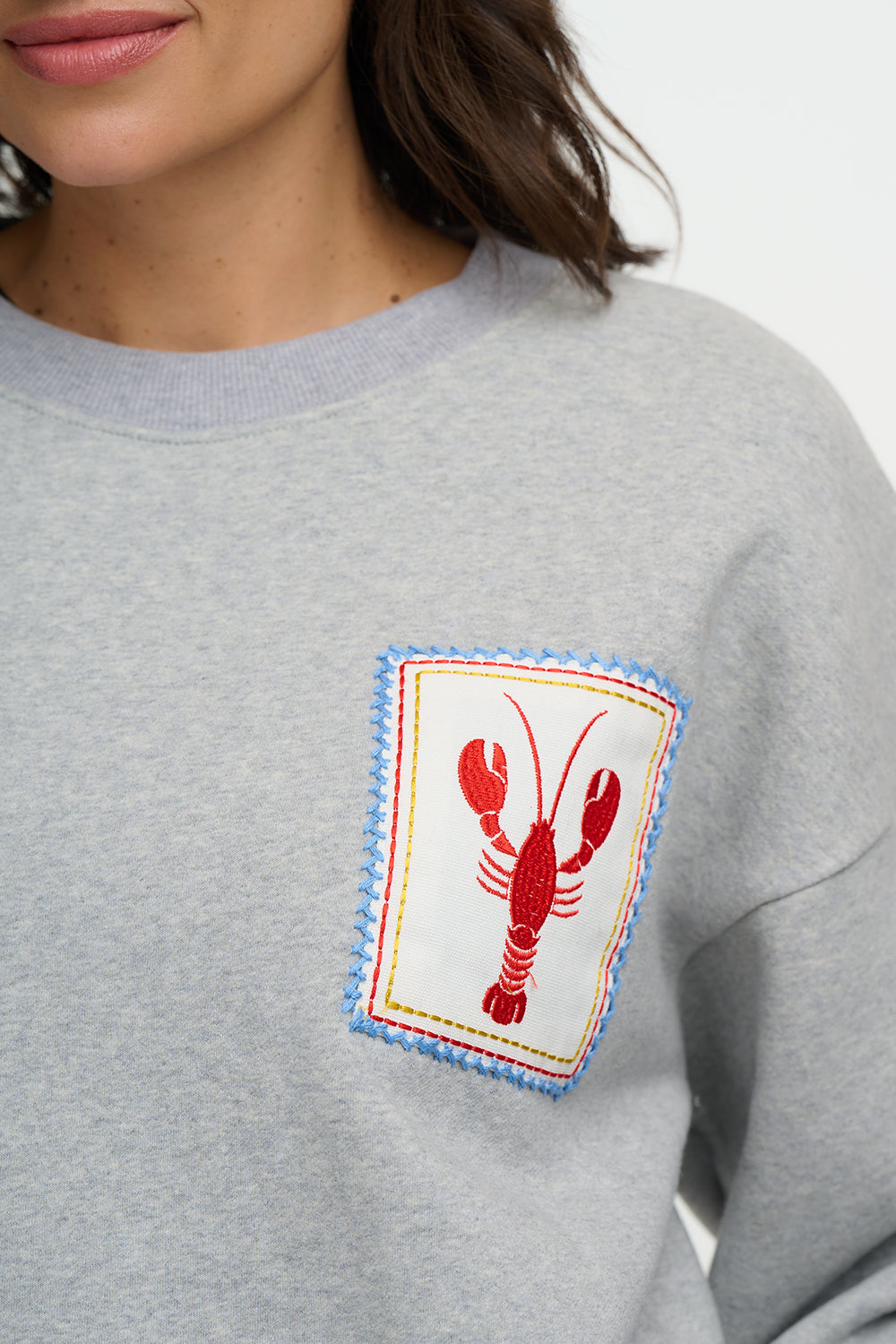 Gray sweatshirt with a red lobster patch on a white background