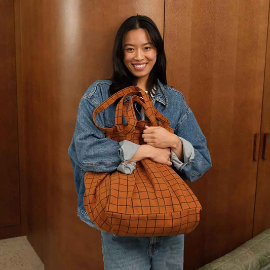 Woman holding an orange textured bag against a wooden background