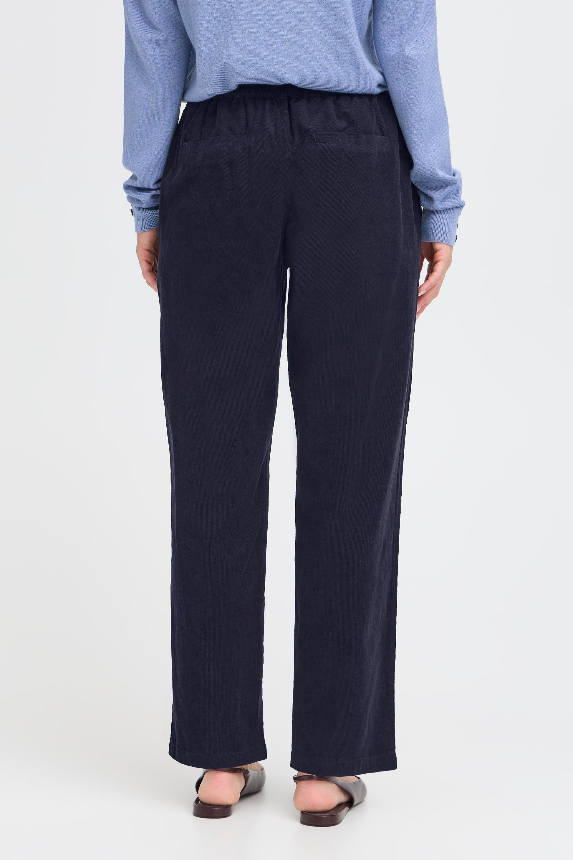 Person wearing navy pants and a light blue shirt on a white background
