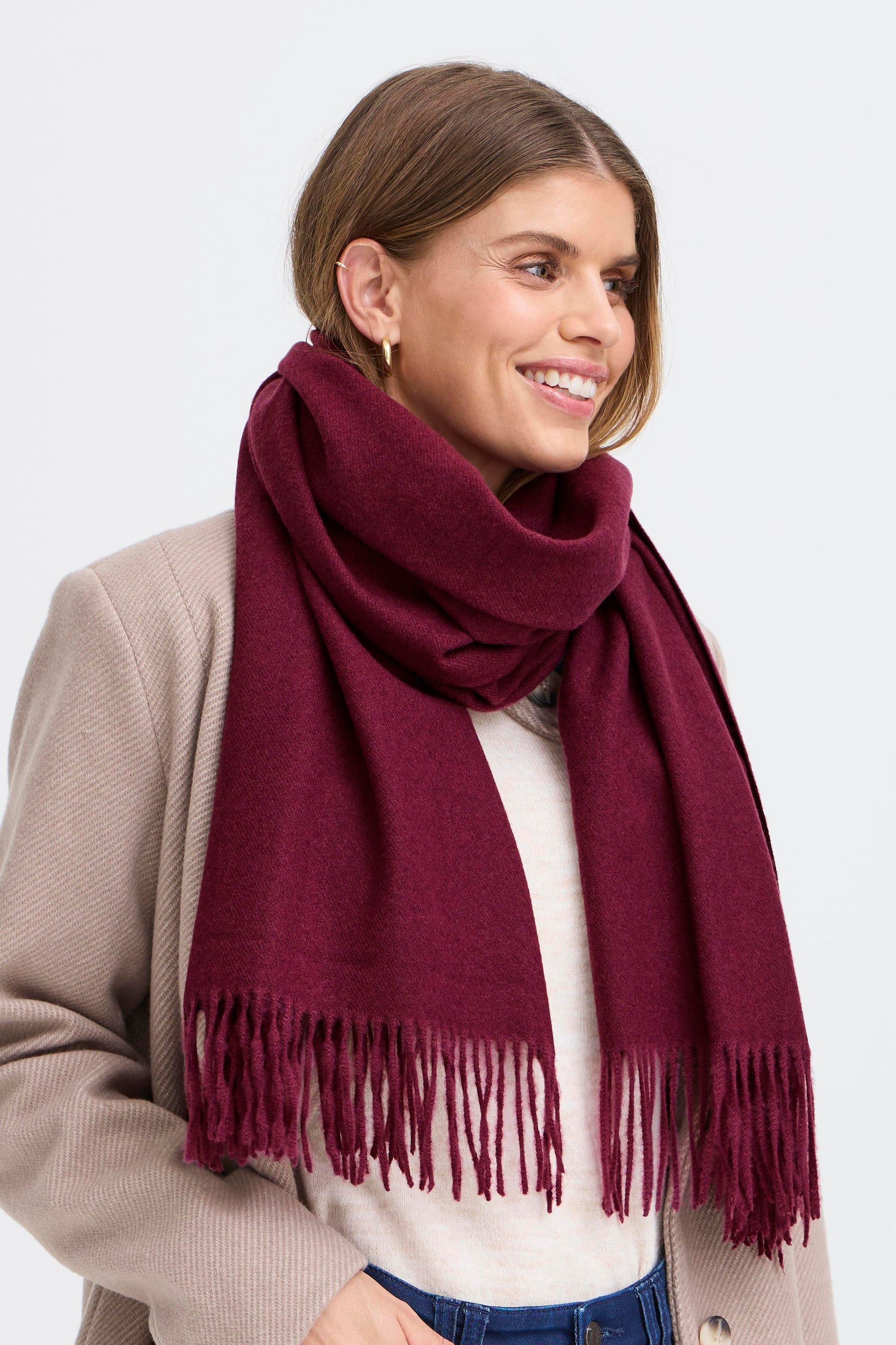 Woman wearing a burgundy scarf with a plain background