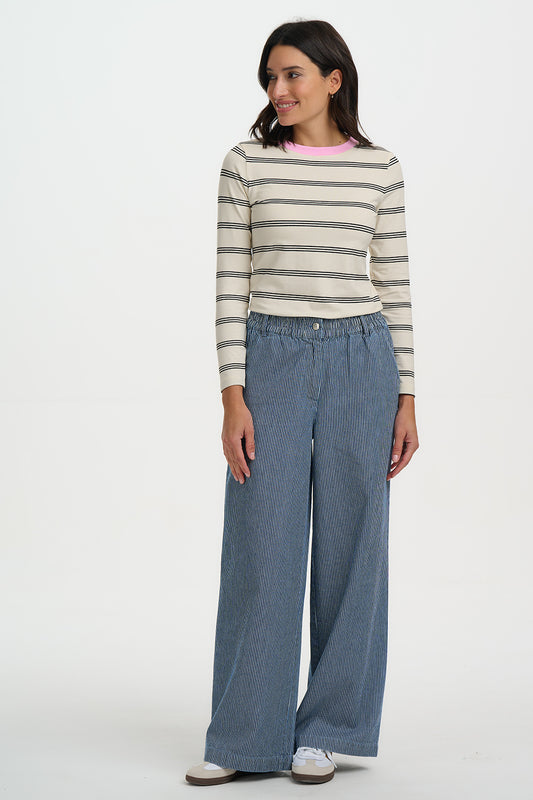 Woman wearing a striped sweater and wide-leg jeans on a white background