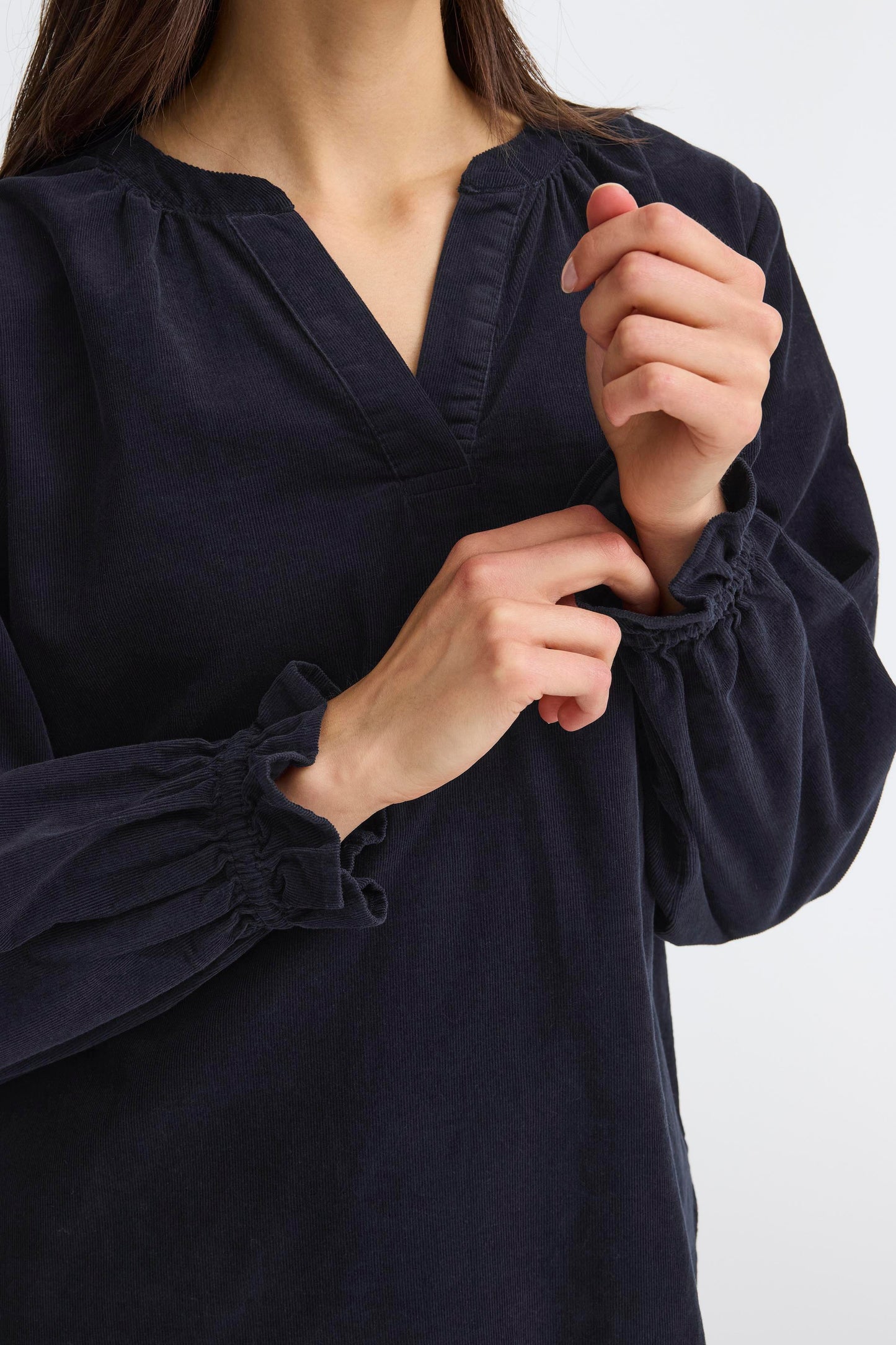 Navy blue blouse with long sleeves and gathered cuffs on a white background