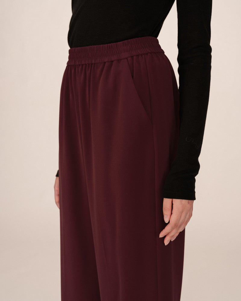Maroon skirt worn by a person on a beige background