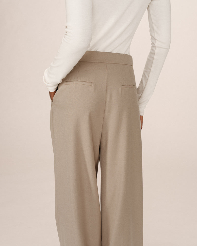 Beige pants worn by a person on a plain background