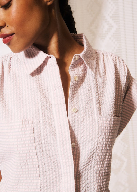 Close-up of a textured white shirt worn by a person against a neutral background
