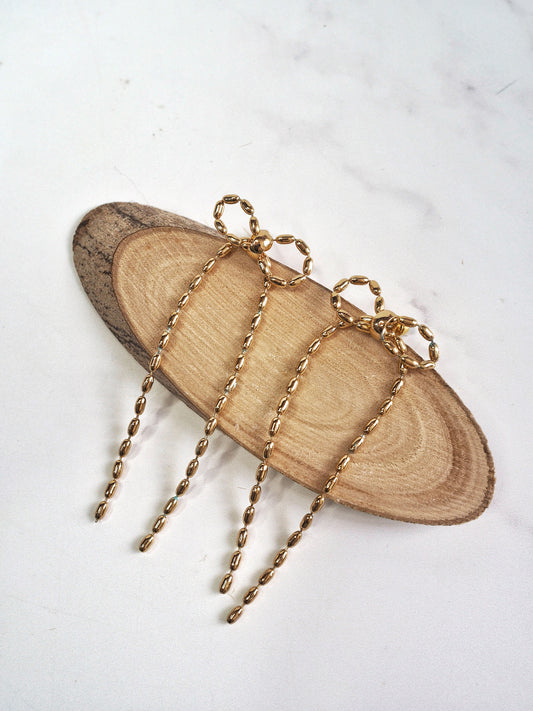 Gold Bow shaped earrings on a wooden shape and white background