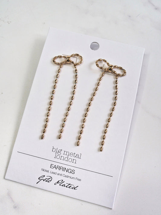 Gold bow-shaped earrings on a 'big metal london' card with gold plating text.
