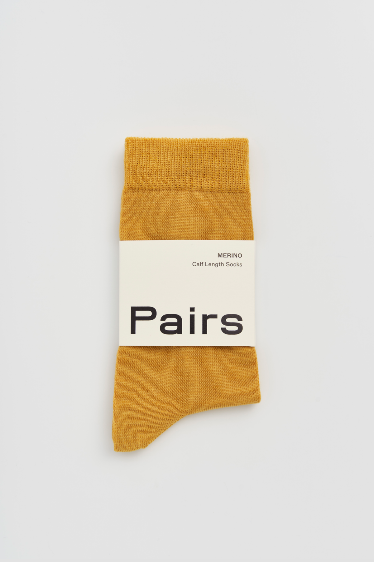 Mustard yellow sock with a white label on a light gray background