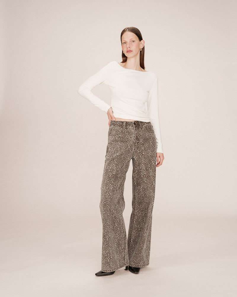 Woman wearing a white top and patterned pants on a plain background