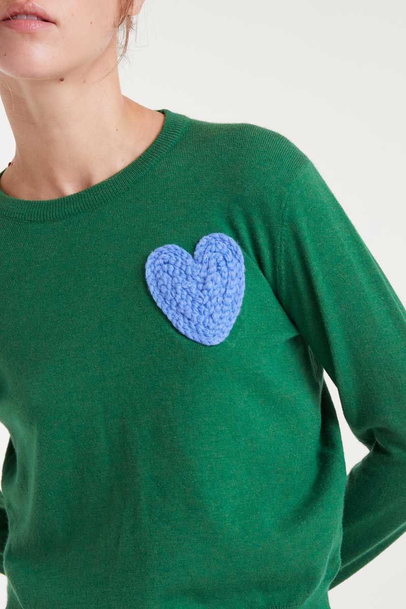 Green sweater with a blue heart patch worn by a person