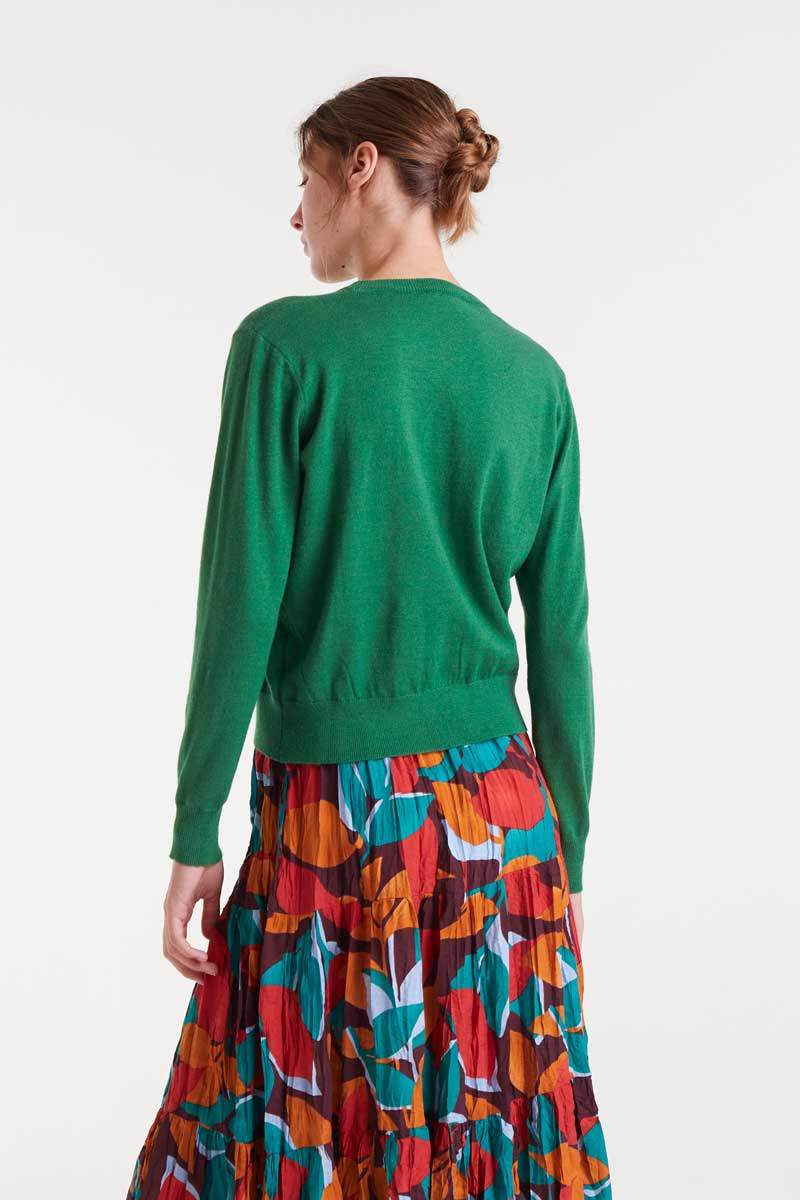 Person wearing a green sweater and colorful patterned skirt on a white background