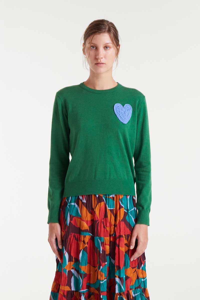 Woman wearing a green sweater with a purple heart design on a white background