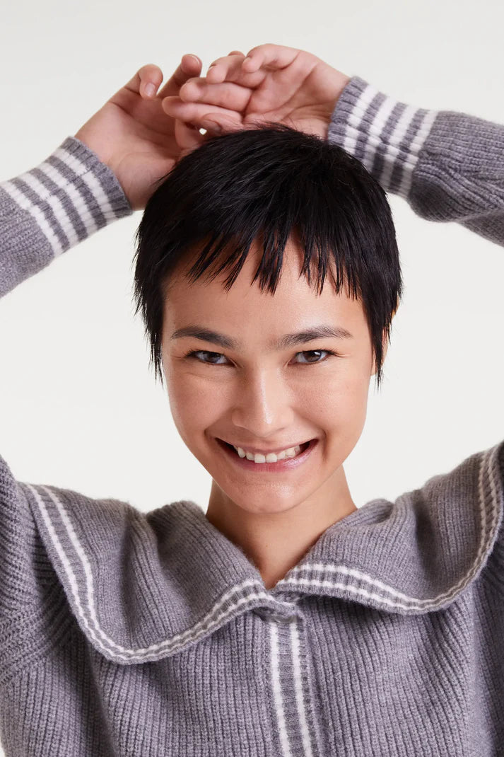 Person wearing a gray sweater with a white collar against a white background