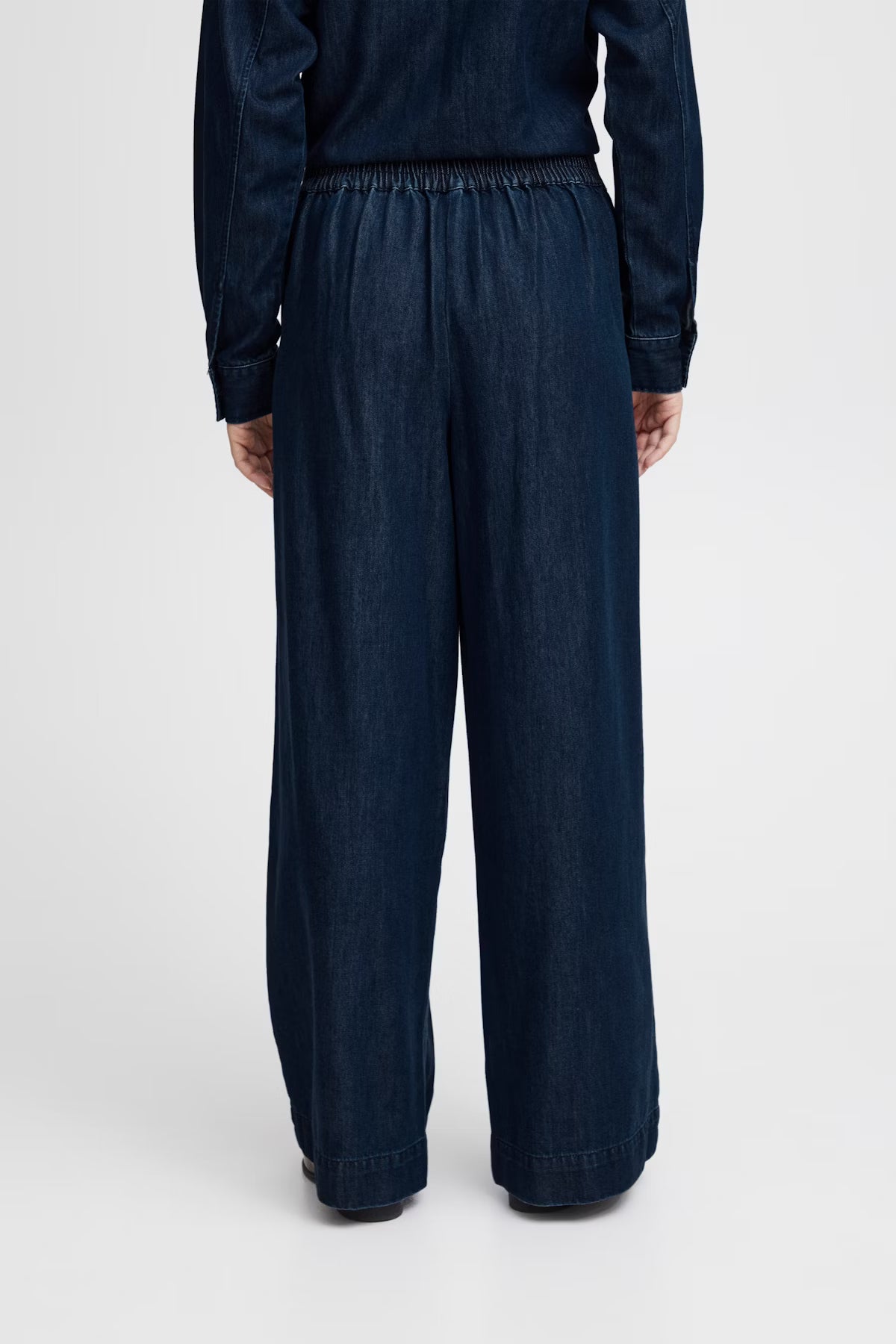 Person wearing dark blue wide-leg pants on a white background