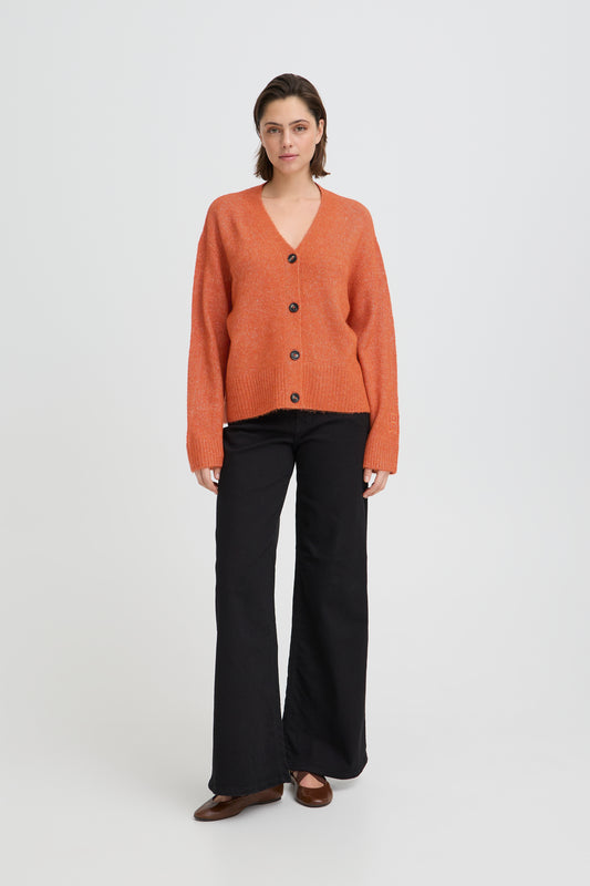 Woman wearing an orange cardigan and black pants on a white background