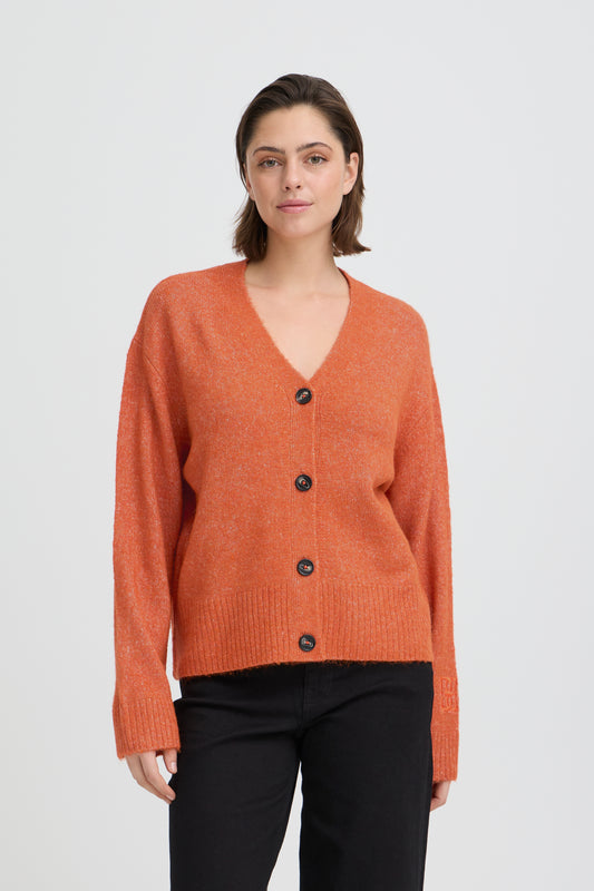 Woman wearing an orange cardigan with black buttons on a white background