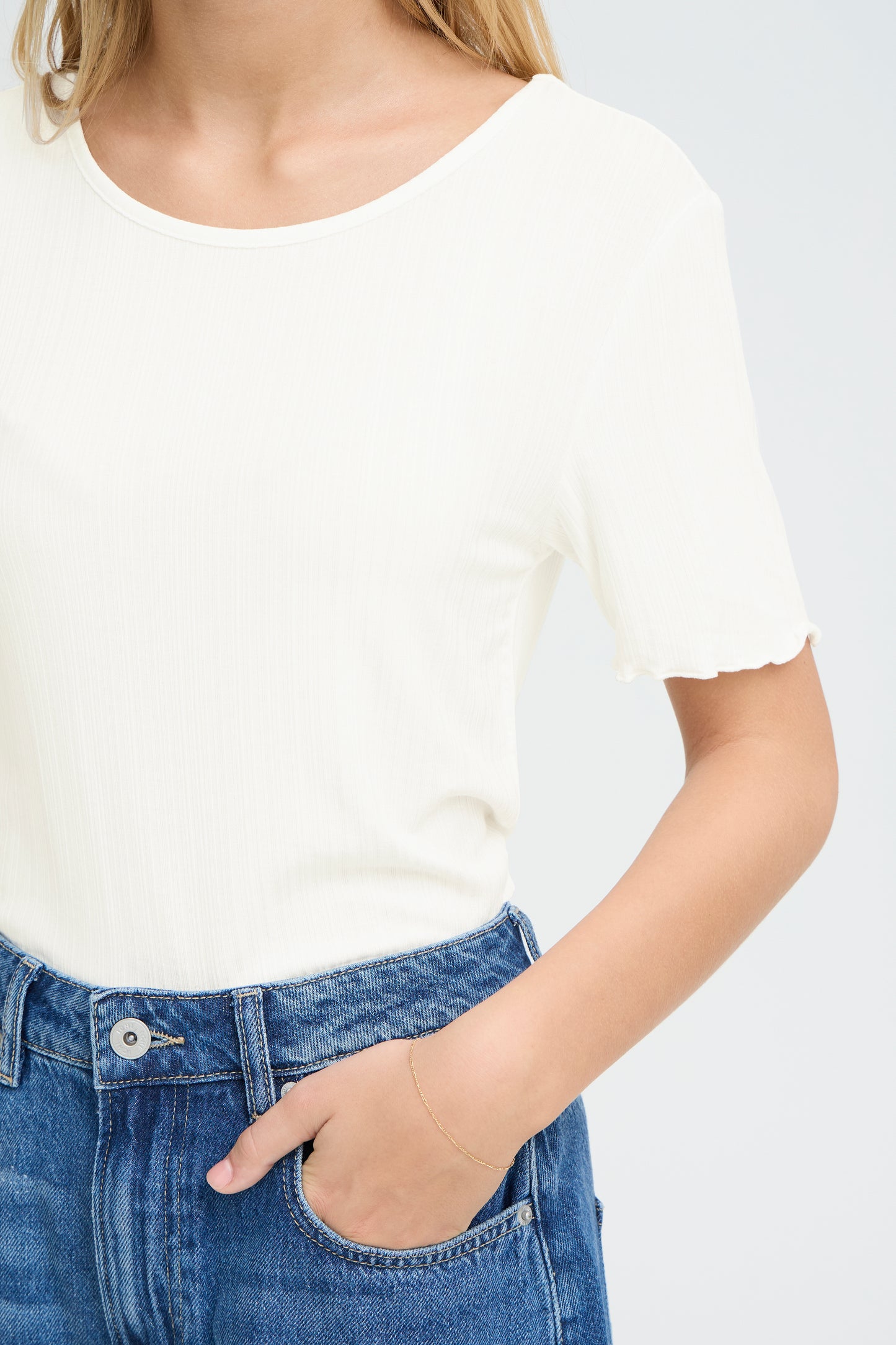 Person wearing a white t-shirt and blue jeans on a plain background