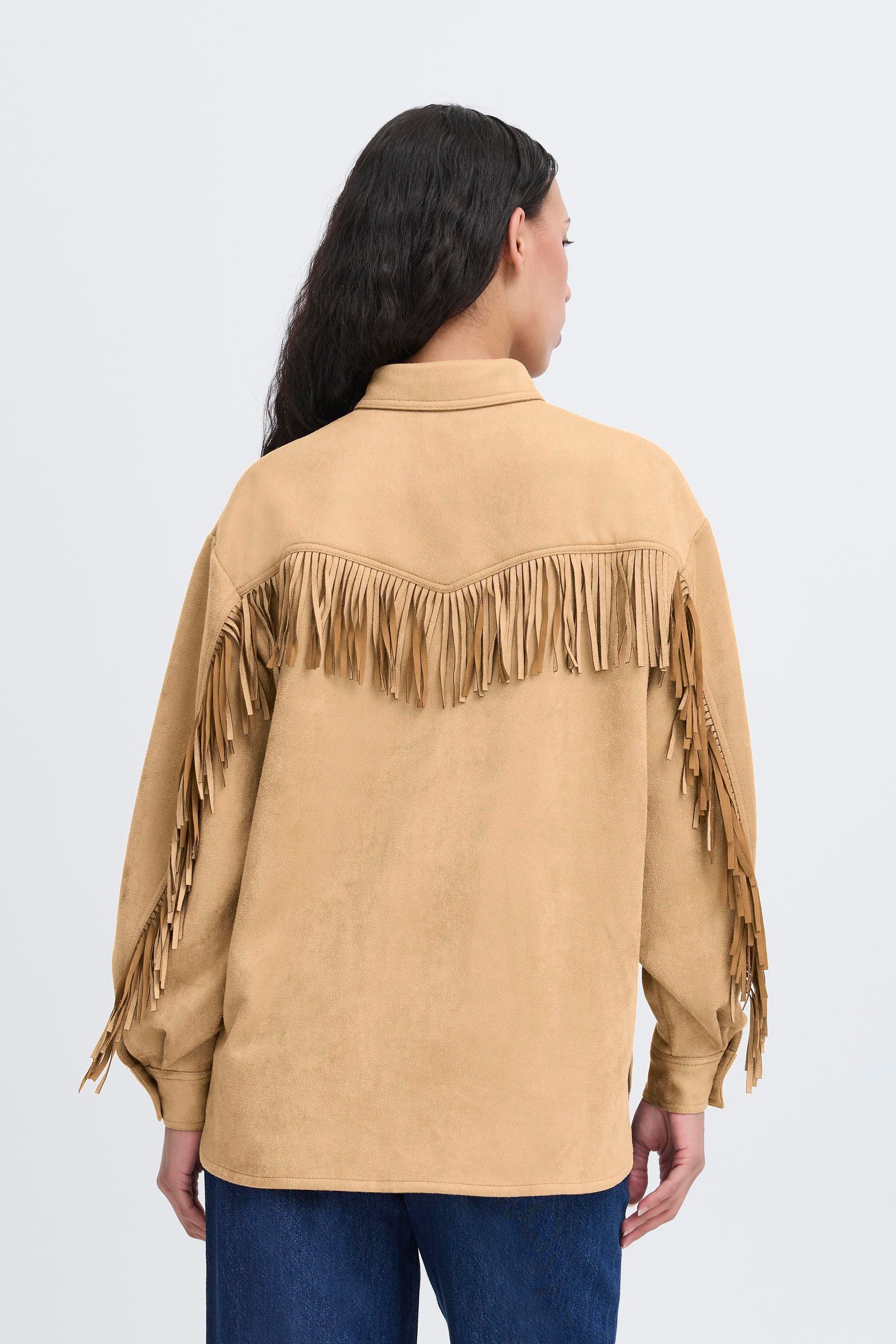Woman wearing a beige suede jacket with fringe details on a white background