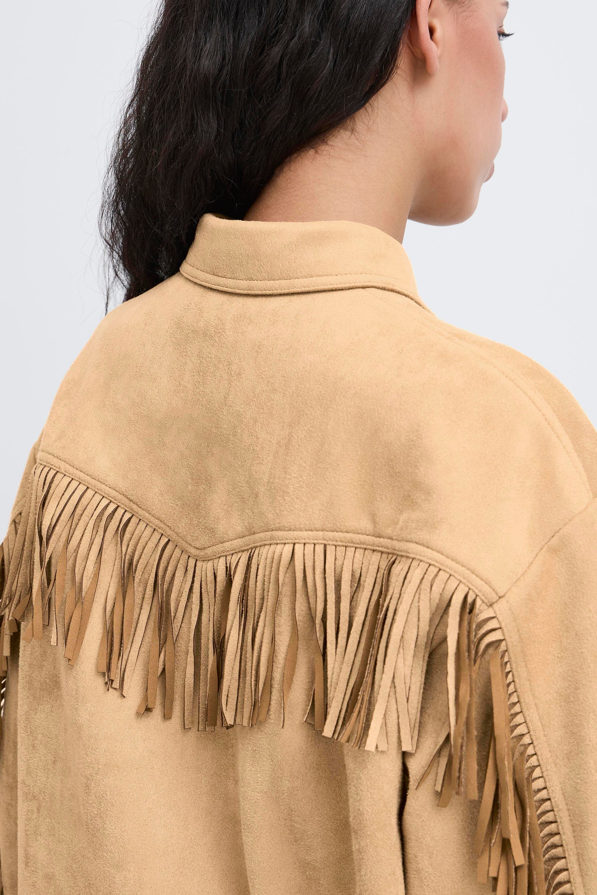 Beige suede jacket with fringe details on a plain background
