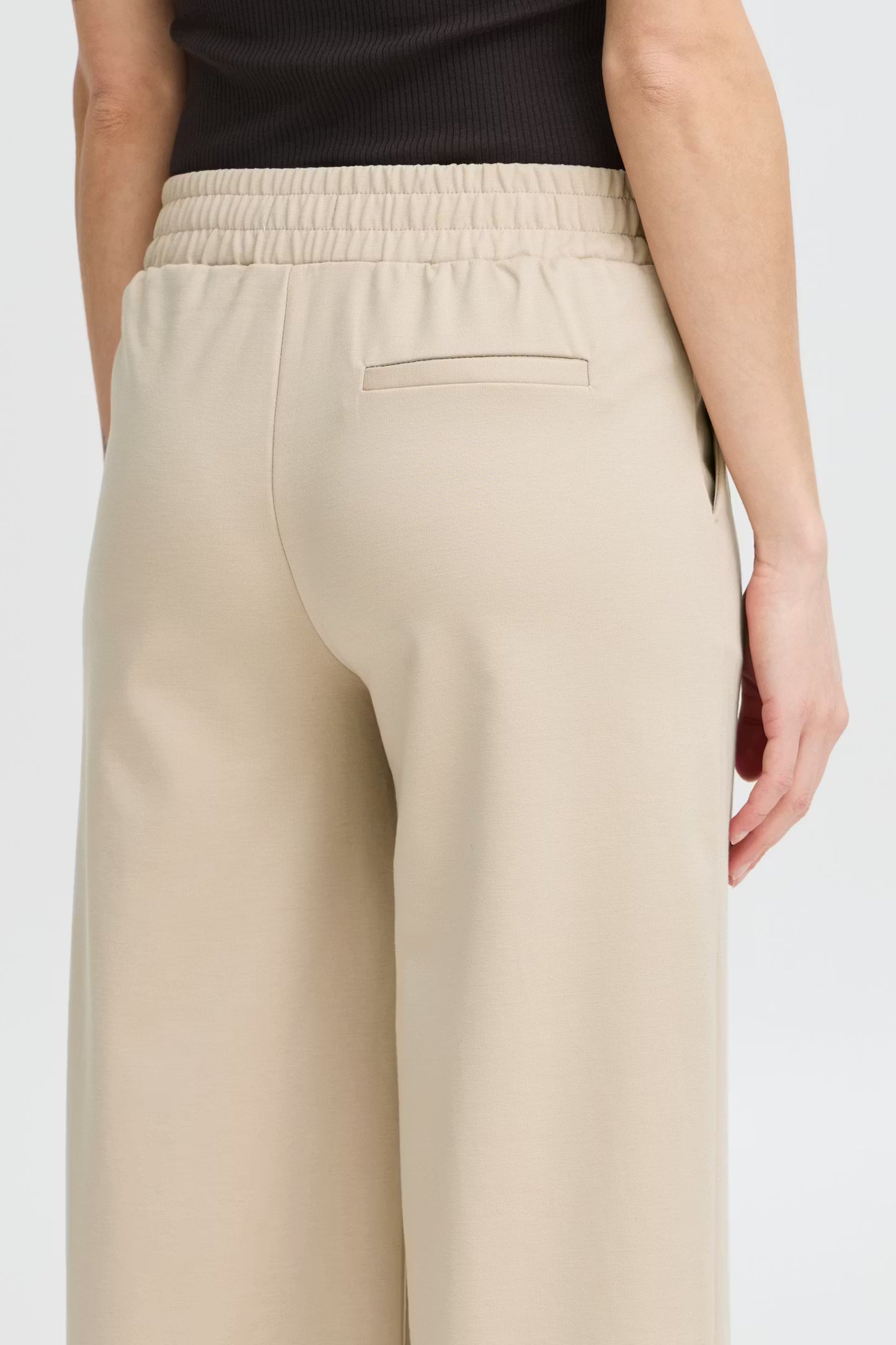 Beige pants worn by a person on a white background