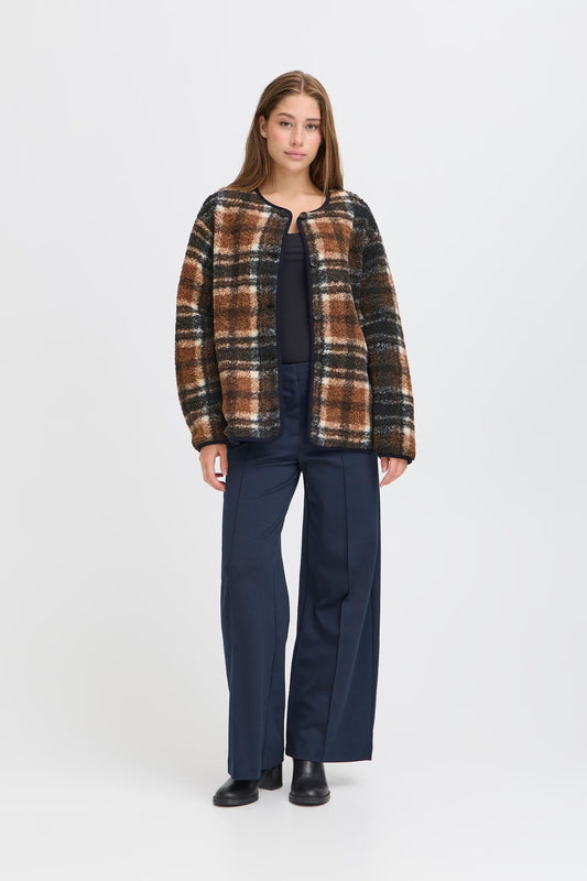 Woman wearing a plaid jacket and navy pants on a white background