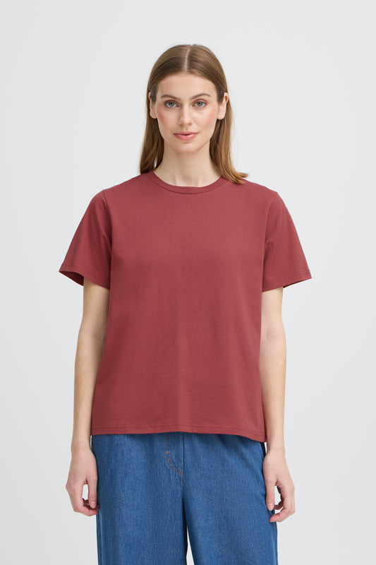 Person wearing a maroon t-shirt and blue jeans on a white background