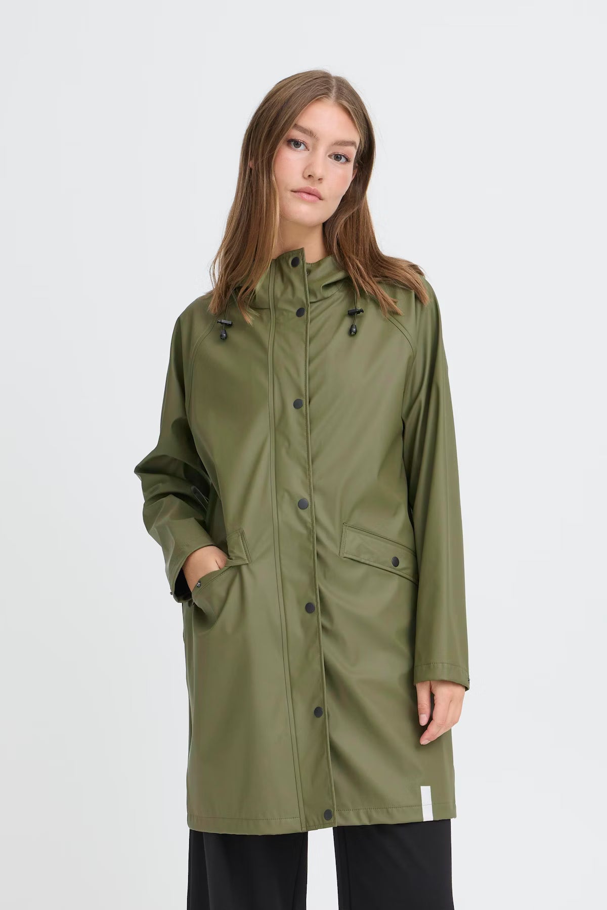 Woman wearing a green raincoat on a white background