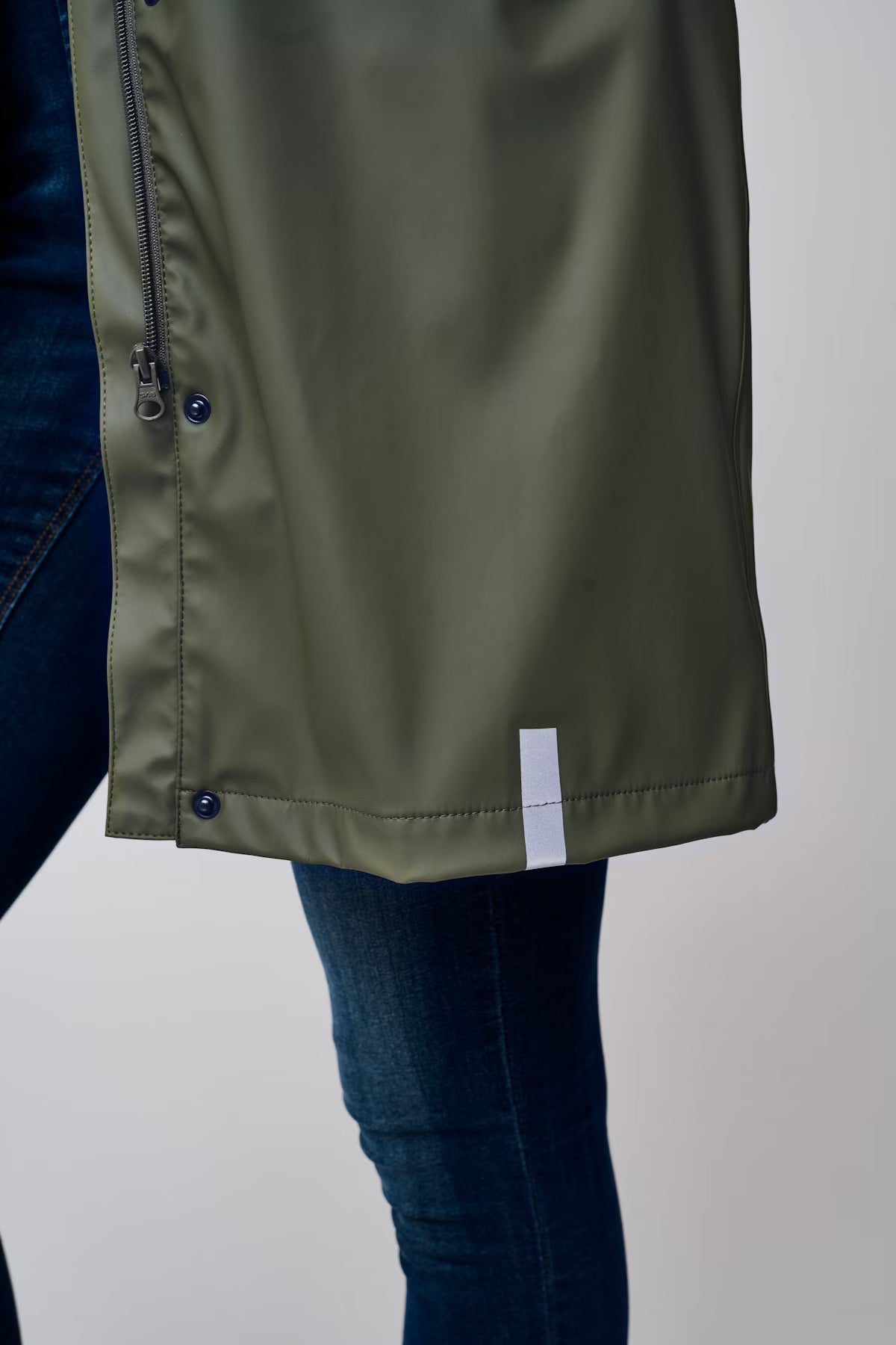 Green raincoat with blue jeans on a plain background