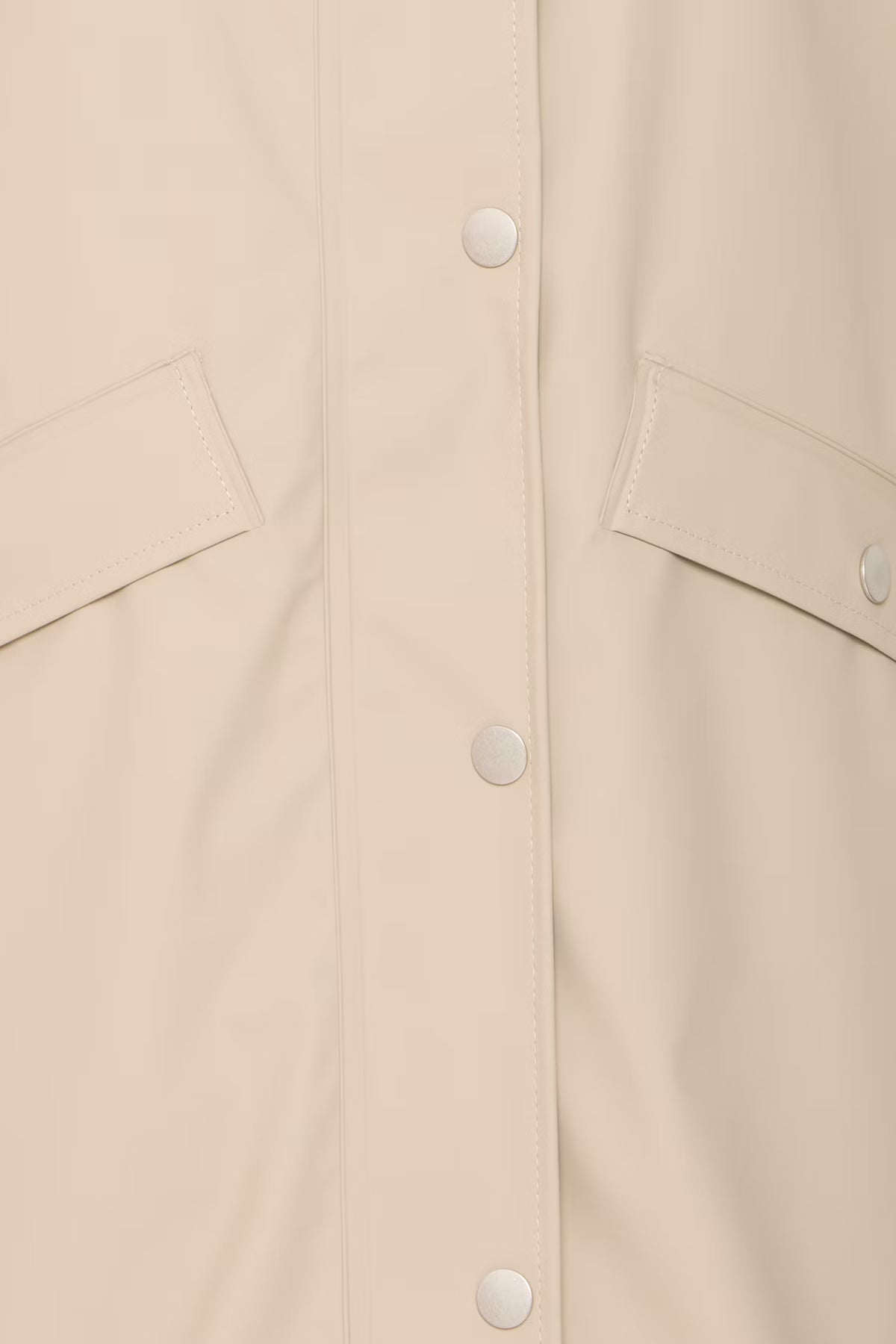 Close-up of a beige jacket with button details on a beige background