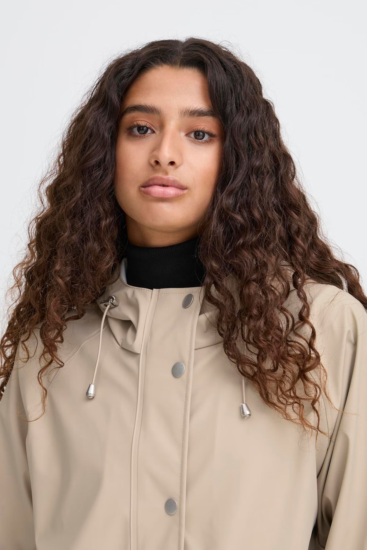 Woman wearing a beige coat with a plain background