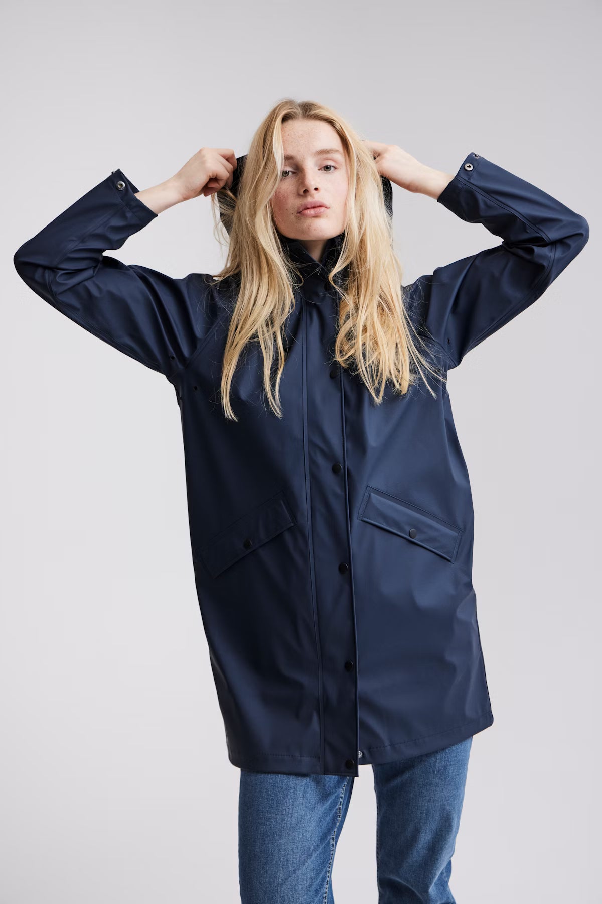 Person wearing a navy raincoat on a plain background
