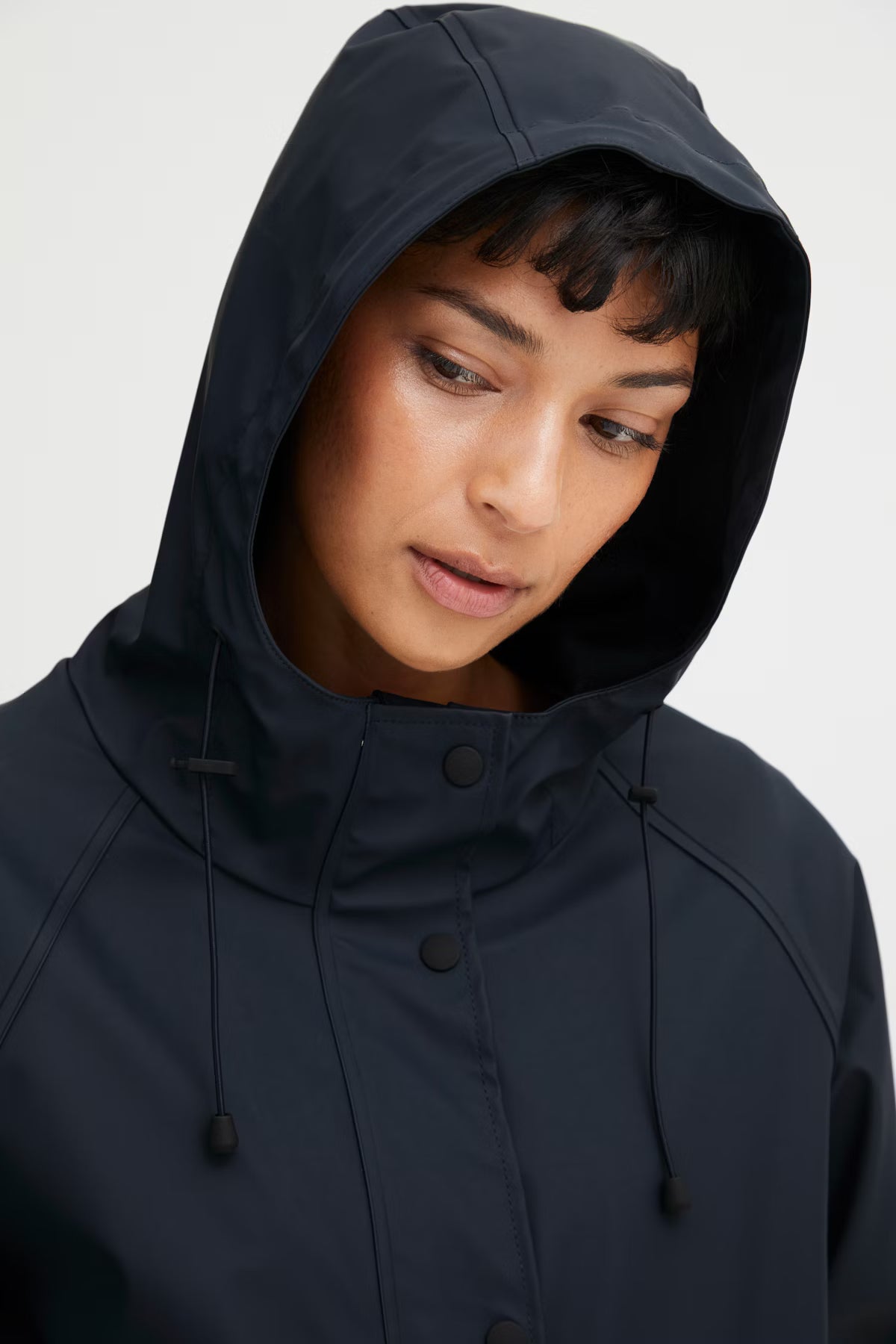 Person wearing a dark blue hooded jacket against a white background
