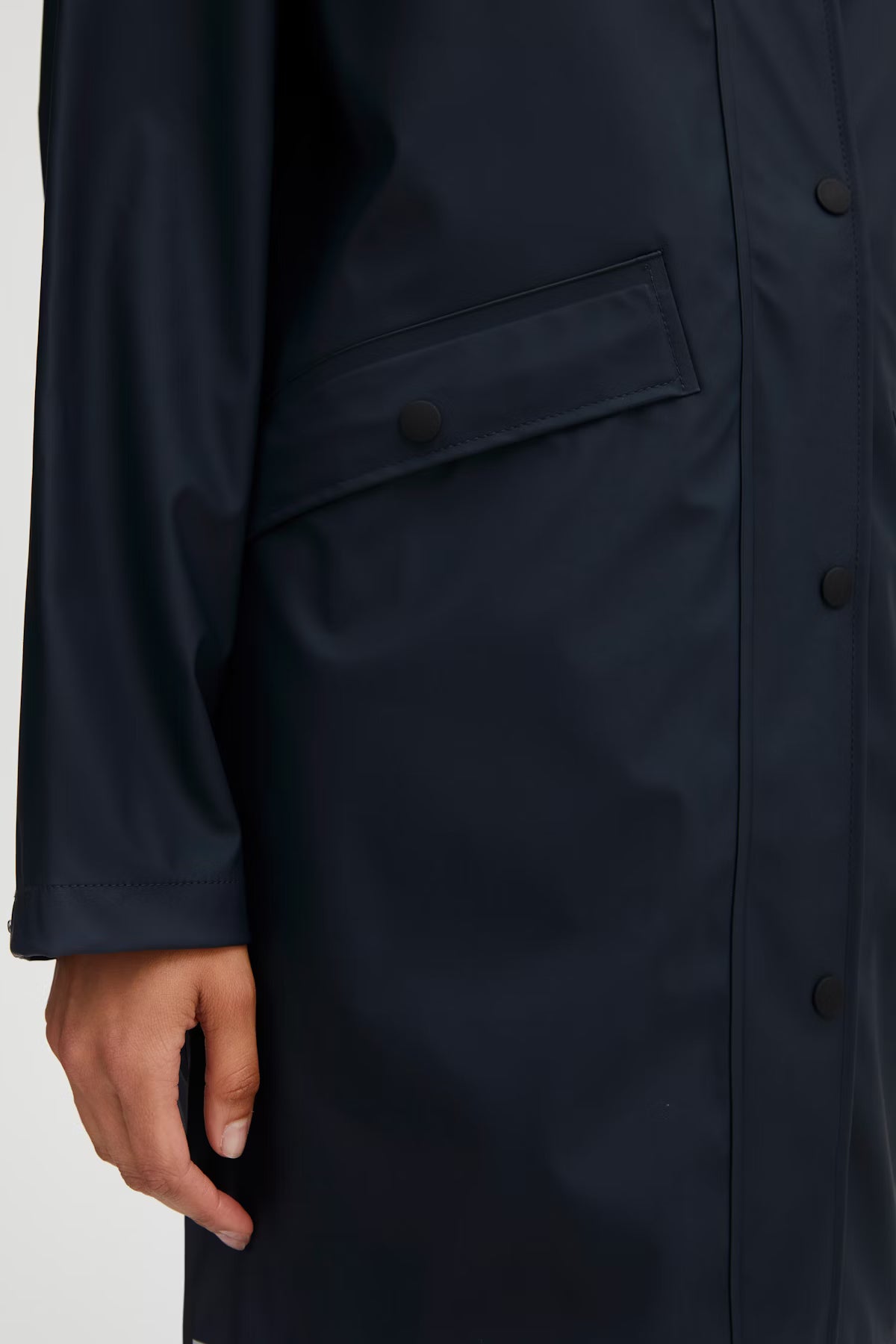 Navy raincoat with a buttoned pocket on a white background