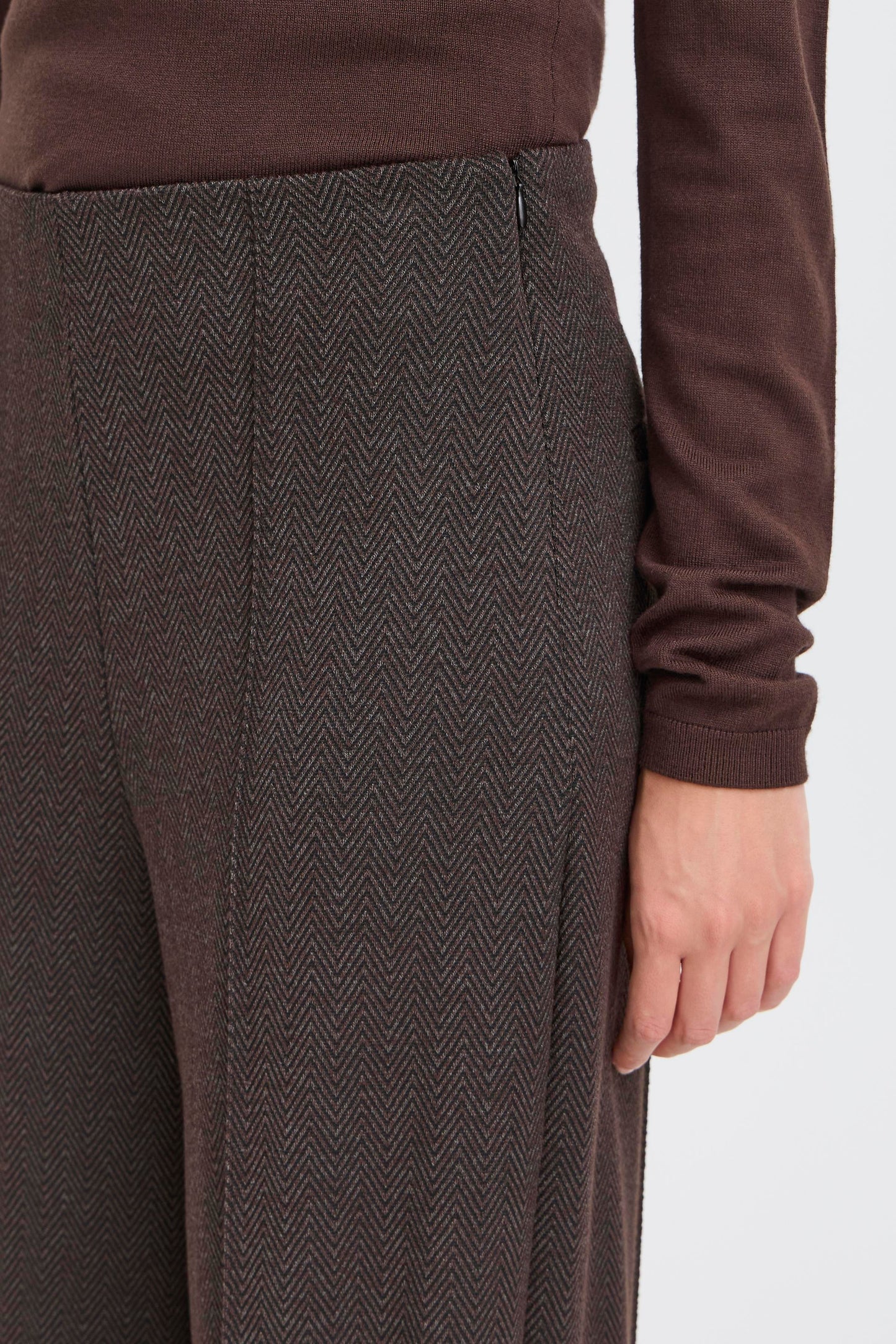 Brown sweater and herringbone-patterned pants on a white background