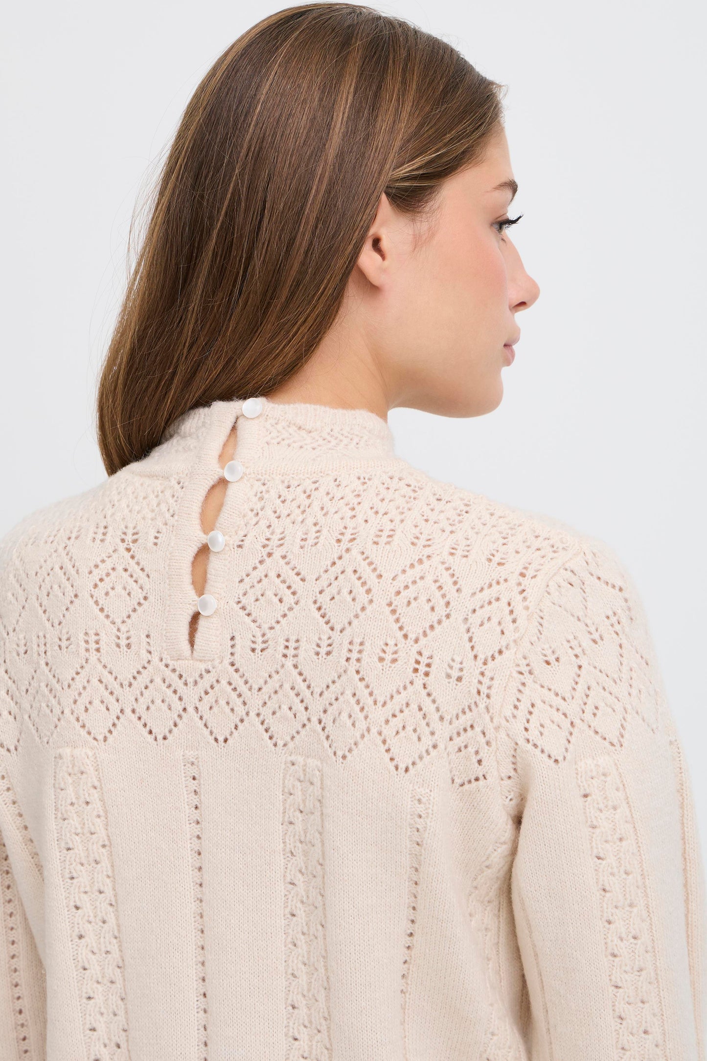 Woman wearing a beige knitted cardigan with a white background