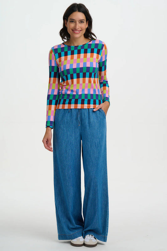 Woman wearing a colorful checkered top and blue pants on a white background