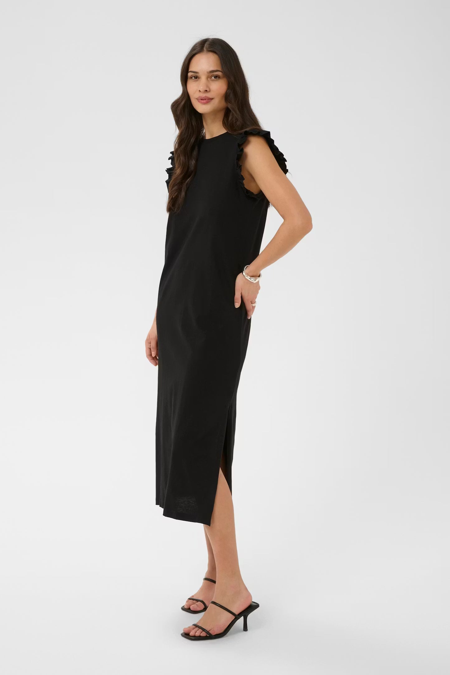 Woman wearing a black sleeveless dress with a slit on a white background