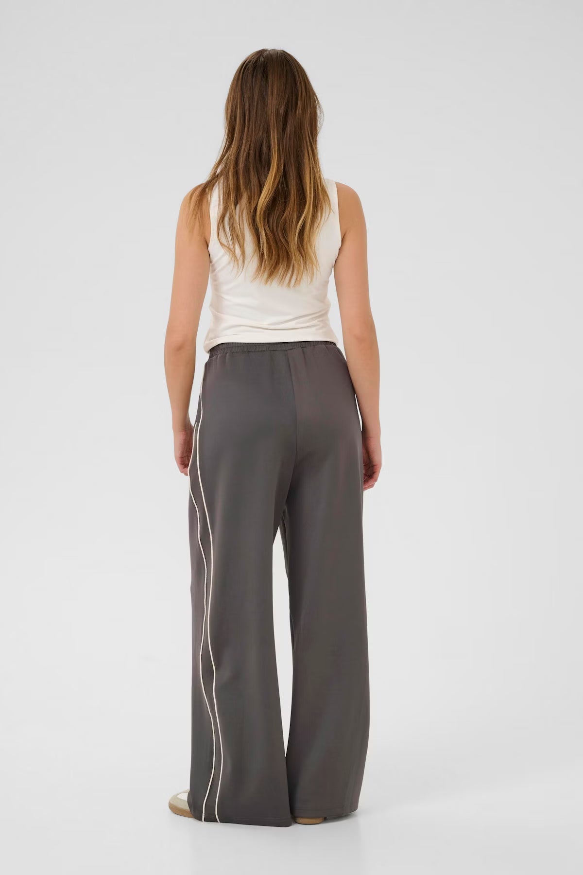 Woman wearing gray pants with white stripes on a white background