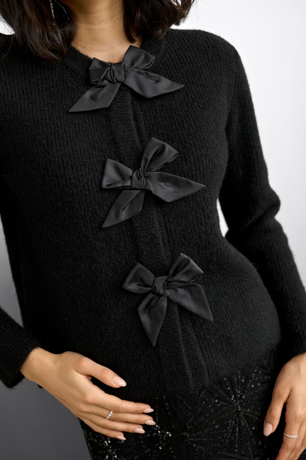 Black cardigan with bow details on a white background