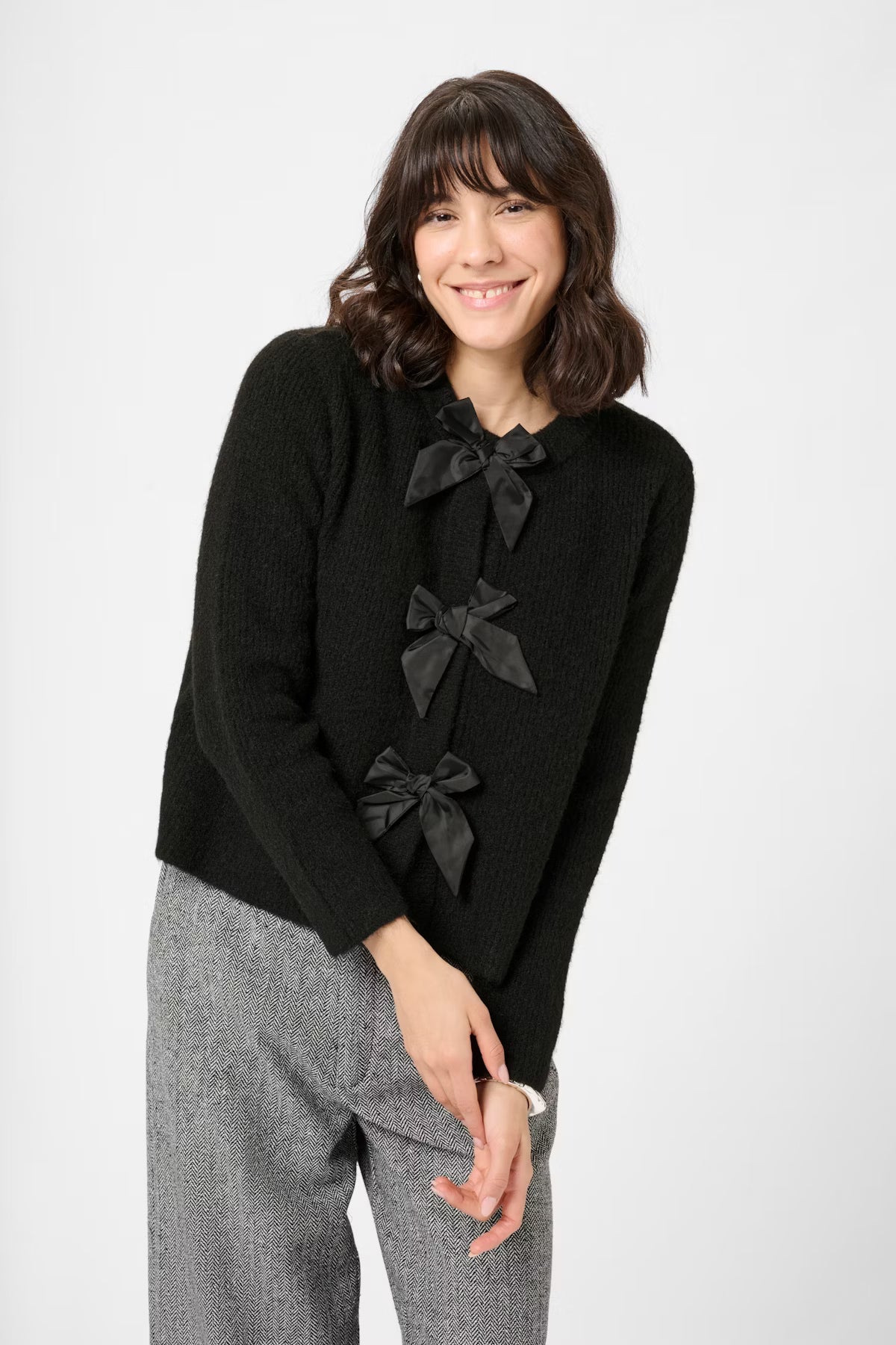 Woman wearing a black sweater with bow details on a white background