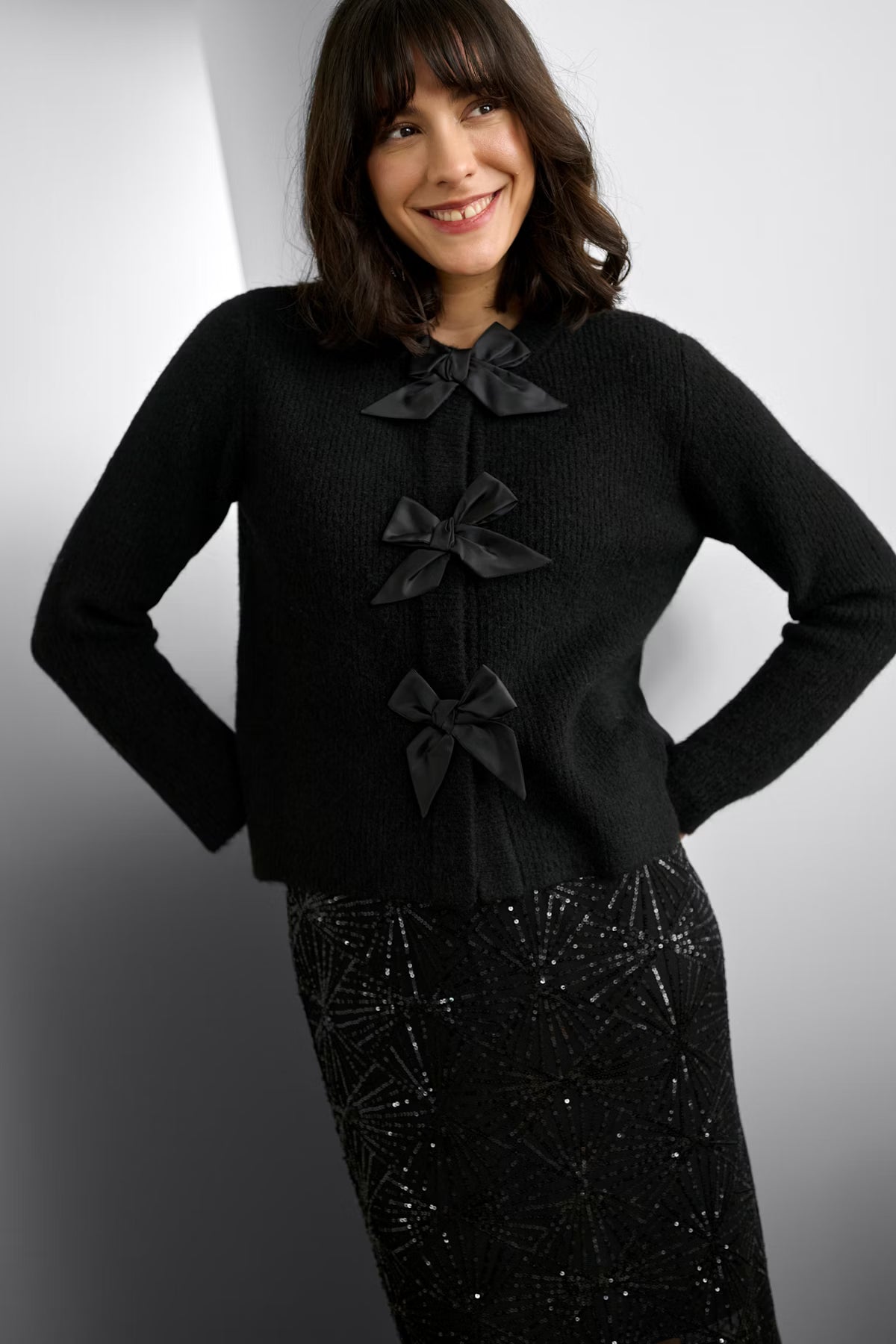 Woman wearing a black outfit with bow details on a gradient background