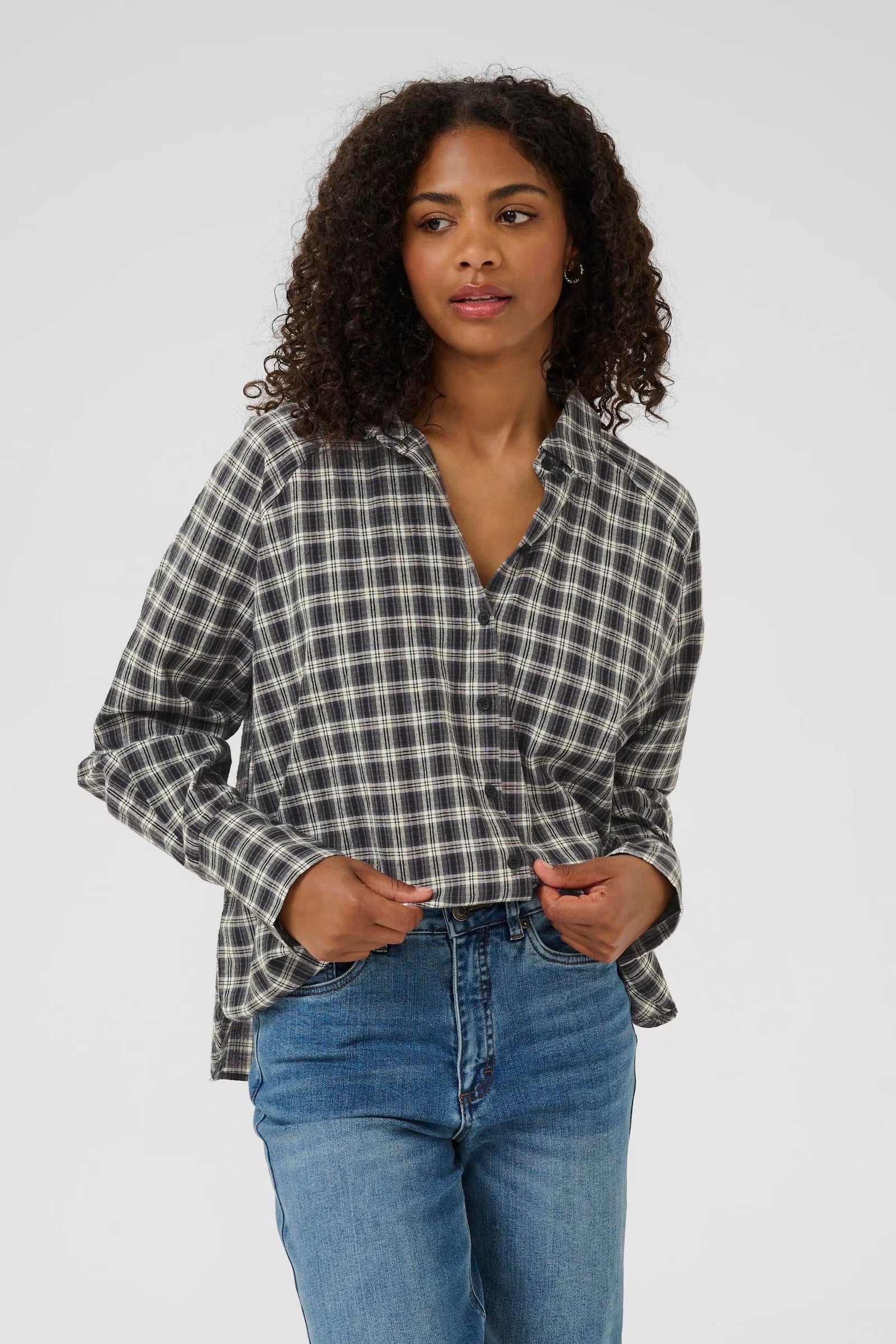 Woman wearing a plaid shirt and blue jeans on a white background