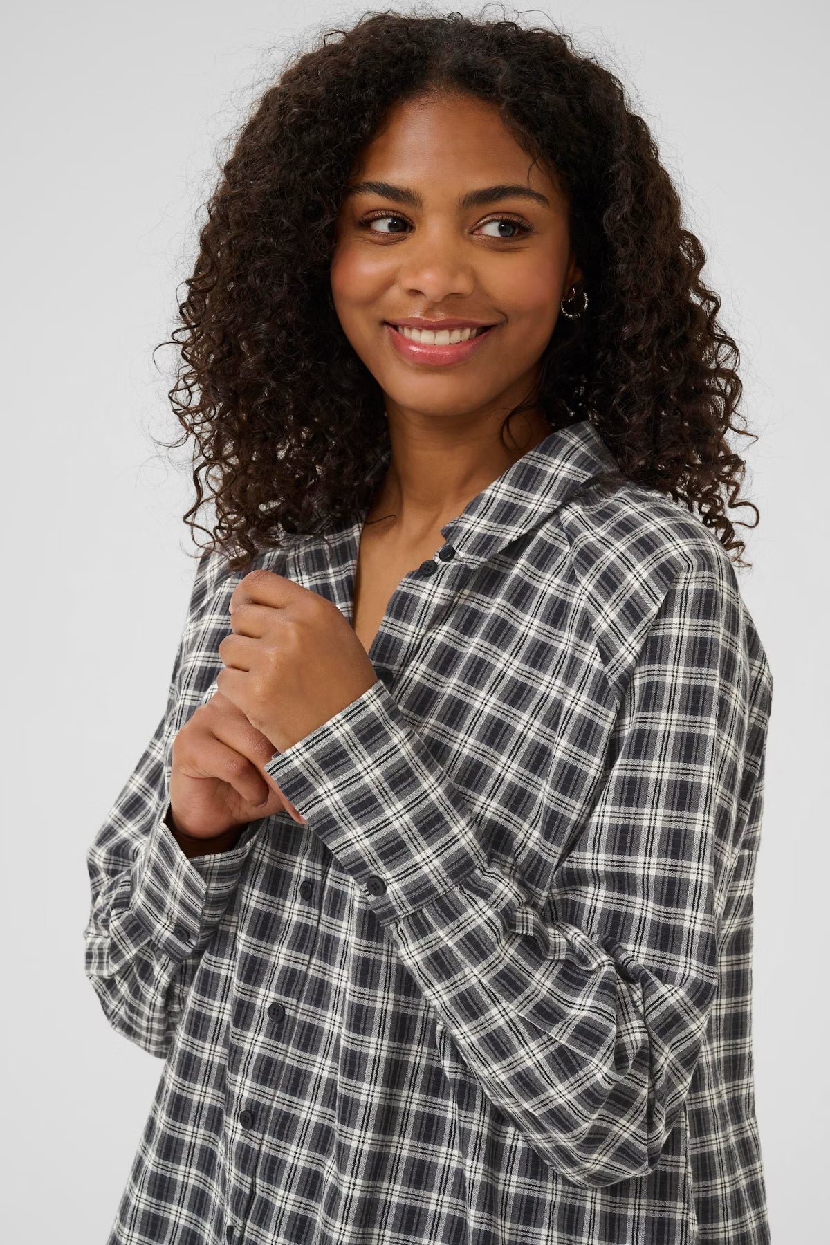 Woman wearing a plaid shirt against a plain background